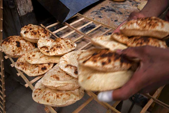 A worker collects Egyptian traditional 'baladi' flatbread, at a bakery, in el-Sharabia, Shubra district, Cairo, Egypt on March 2, 2022.