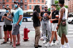 People gather on a street in the Hell's Kitchen neighborhood of New York while waiting to get takeout drinks at a bar on May 29, 2020.