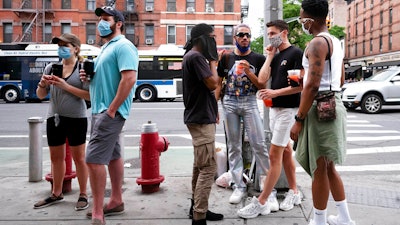 People gather on a street in the Hell's Kitchen neighborhood of New York while waiting to get takeout drinks at a bar on May 29, 2020.