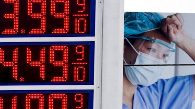 Prices are displayed on a sign at a gas station in Milwaukee on March 14, 2022, with a billboard for medical services in the background.