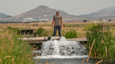 Justin Grant watches water flow from his agricultural well, Klamath Falls, Ore., July 24, 2021.