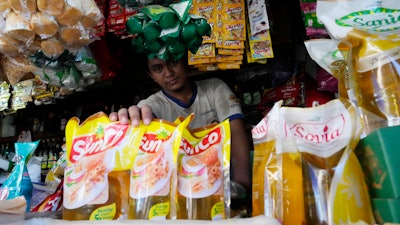 A vendor shows packs of cooking oil at his stall at a market in Jakarta, April 17, 2022.