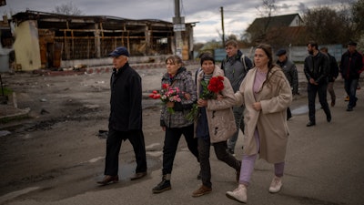Tetyana Boikiv, 52, center, walks with family members and neighbors during a funeral service for her husband, Mykola Moroz, 47, at the Ozera village near Bucha, Ukraine, April 26, 2022.