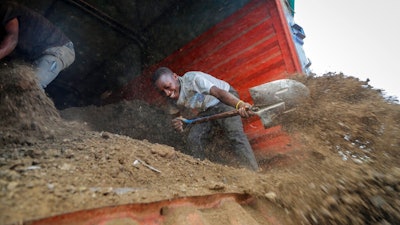 Farmers offload livestock manure from a truck, that will be used to fertilize crops due to the increased cost of fertilizer that they say they now can't afford to purchase, in Kiambu, near Nairobi, in Kenya Thursday, March 31, 2022. Russia's war in Ukraine has pushed up fertilizer prices that were already high, made scarce supplies rarer still and squeezed farmers, especially those in the developing world struggling to make a living.