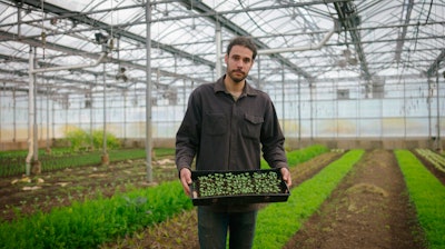 In this photo provided by the Rockefeller Foundation, Jason Grauer, the Seed and Crop Director at Stone Barns, poses for a photo at Stone Barns’s greenhouse on April 7, 2021, in Tarrytown, N.Y. Rockefeller grantee Stone Barns Center for Food and Agriculture is working on innovative, community-based ways to increase access to food and use sustainable environmental practices.