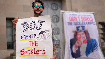 Nicholas Rivers of Maine, holds a sign that reads DOJ Hammer the Sacklers' during a protest with advocates for opioid victims outside the Department of Justice, Friday, Dec. 3, 2021, in Washington. A federal appeals panel is scheduled to hear arguments on whether members of the Sackler family can be granted protection from lawsuits as part of a bankruptcy settlement for the company they own, OxyContin maker Purdue Pharma. If the company doesn’t get what it wants, it could have to fight off thousands of individual lawsuits.