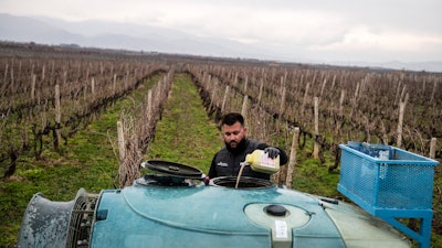 Farmer Dimitris Kakalis, 25, fills a spray machine with pesticide at his vineyard near Tyrnavos, Greece, Feb. 13, 2022.