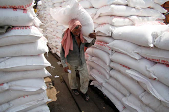 A laborer carries a sack of sugar at a warehouse in Jammu, India, Aug. 22, 2013.
