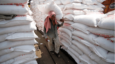 A laborer carries a sack of sugar at a warehouse in Jammu, India, Aug. 22, 2013.