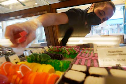 Beth Duckworth fills a display cabinet with sweet treats at The Goldenrod, a popular restaurant and candy shop in York Beach, Maine, June 1, 2022.