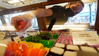Beth Duckworth fills a display cabinet with sweet treats at The Goldenrod, a popular restaurant and candy shop in York Beach, Maine, June 1, 2022.