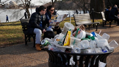 A trash can overflows as people sit outside of the Martin Luther King Jr. Memorial, Washington, D.C., Dec. 27, 2018.