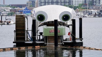 Mr. Trash Wheel, a mechanism that collects trash from tributaries that feed into Baltimore's Inner Harbor sits in the water, Friday, May 13, 2022, in Baltimore. Many novel devices are being used or tested worldwide to trap plastic trash in rivers and smaller streams before it can get into the ocean. Officials say Mr. Trash Wheel has inspired fans to begin recycling or join trash cleanups.