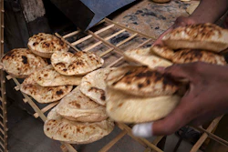 A worker collects Egyptian traditional 'baladi' flatbread at a bakery in the el-Sharabia, Shubra district, Cairo, March 2, 2022.