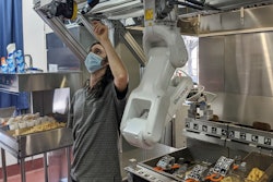 A technician makes an adjustment to a robot at Miso Robotics' White Castle test kitchen.