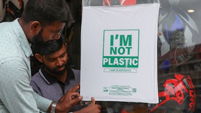 Workers paste degradable plastic substitute material on glass, Hyderabad, India, June 30, 2022.