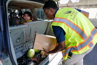 A volunteer fills a vehicle with food boxes at the St. Mary's Food Bank, Phoenix, June 29, 2022.