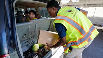 A volunteer fills a vehicle with food boxes at the St. Mary's Food Bank, Phoenix, June 29, 2022.
