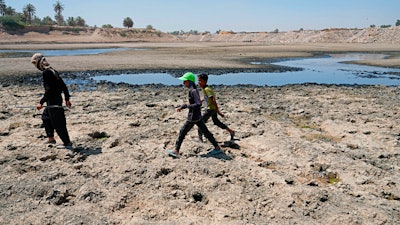 People cross the Diyala River near Baghdad, June 29, 2022.