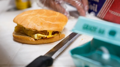 Hector Perez prepares to wrap a bacon, egg and cheese sandwich at a bodega, the Bronx, New York, July 22, 2022.