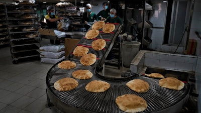 Workers package bread coming off a production line at an automated bakery in Dahiyeh, Lebanon, March 15, 2022.