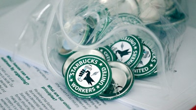Pro-union pins sit on a table during a watch party for Starbucks' employees union election, Dec. 9, 2021, Buffalo, N.Y.