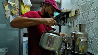 An Indian tea seller who gave his name as Rafik pours karak in Dubai, United Arab Emirates, Aug. 24, 2022.