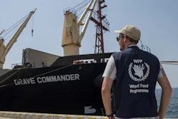 A member of the World Food Programme next to the Brave Commander bulk carrier ship at the port of Djibouti city, Djibouti, Aug. 30, 2022.