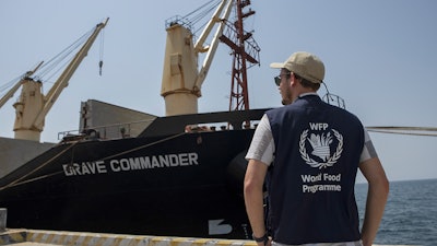 A member of the World Food Programme next to the Brave Commander bulk carrier ship at the port of Djibouti city, Djibouti, Aug. 30, 2022.