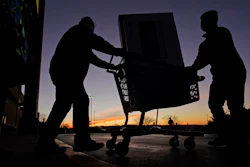 People carry a television to their car at a Best Buy store, Overland Park, Kan., Nov. 26, 2021.