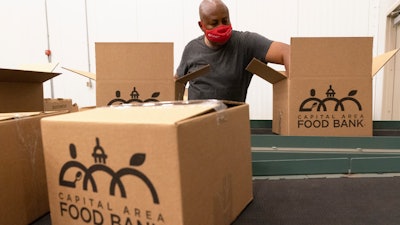 A volunteer pack boxes of food at The Capital Area Food Bank in Washington, Oct. 5, 2021.