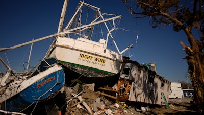 Damaged shrimp boats and debris litter the waterfront at Erickson & Jensen Seafood, San Carlos Island, Fort Myers Beach, Fla., Oct. 7, 2022.