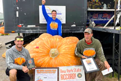 In this photo provided by The Great Pumpkin Farm, Emmett Andrusz, from left, Steve Andrusz and Scott Andrusz, pose with the record setting 2,554-pound pumpkin, in Clarence, N.Y., Saturday, Oct. 1, 2022. Scott Andrusz's entry broke the previous record of 2,528 pounds.