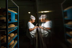 Svitlana Labutcheva, cuts labels by hand for packaging loaves of bread at a bakery in Kostiantynivka, Donetsk region, eastern Ukraine, Saturday, Aug. 20, 2022. Seemingly abandoned during the day, the damaged factory building in eastern Ukraine comes to life at night, when the smell of fresh bread emanates from its broken windows.
