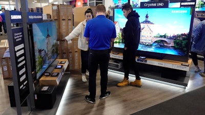 A Best Buy employee helps customers with television selection, Nov. 26, 2021, Indianapolis.