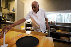 Mani Bhushan, owner of Taco Ocho, puts out table menus at one of his restaurants in McKinney, Texas, Nov. 11, 2022.