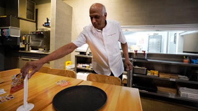 Mani Bhushan, owner of Taco Ocho, puts out table menus at one of his restaurants in McKinney, Texas, Nov. 11, 2022.