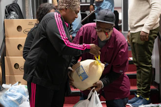 Ricardo Barrett accepts a turkey from volunteer Rita James, left, during a food giveaway at The Redeemed Christian Church of God New Wine Assembly, Washington, Nov. 22, 2022.