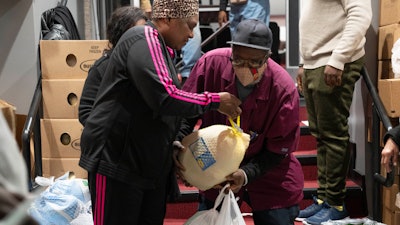 Ricardo Barrett accepts a turkey from volunteer Rita James, left, during a food giveaway at The Redeemed Christian Church of God New Wine Assembly, Washington, Nov. 22, 2022.
