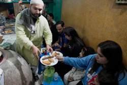 Bilal Sufi, left, owner of Baking Virsa eatery, serves kebabs and naan bread in Lahore, Pakistan, Dec. 3, 2022.