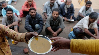 People wait for free food outside an eatery in Ahmedabad, India, Jan. 20, 2021.