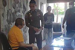Peter Coker Jr., left, is issued search warrants from police at his villa on the southern resort island of Phuket, Thailand, Jan. 11, 2023.