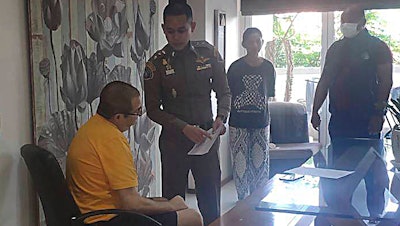 Peter Coker Jr., left, is issued search warrants from police at his villa on the southern resort island of Phuket, Thailand, Jan. 11, 2023.
