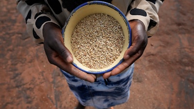 Maria Chagwena, a millet farmer, holds a plate with millet grains outside her house in Zimbabwe's arid Rushinga district, Jan, 18, 2023.