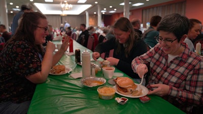 From left, Laura Kuster, Miranda Crotsley and Hollen Barmer eat fish sandwiches, homemade perogies, and macaroni and cheese at the St. Maximilian Kolbe Catholic Church fish fry in Pittsburgh, Feb. 24, 2023.