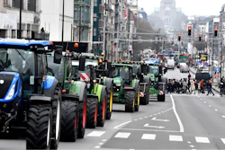 Pedestrians cross a street as farmers block traffic during a demonstration in Brussels, March 3, 2023.