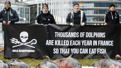 Activists stand by dead dolphins they spread in front of the European parliament in Strasbourg, France, March 14, 2023.