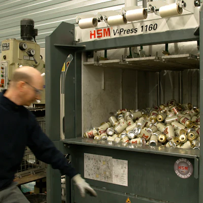 A worker prepares to press the button of a machine to crush empty Miller High Life beer cans at the Westlandia plant in Ypres, Belgium, April 17, 2023.