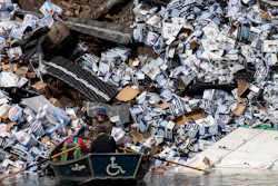 Fishermen claim a bottle of beer from a derailed railcar on the banks of the Clark Fork River near Quinn's Hot Springs, Mont., April 2, 2023.