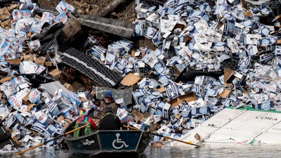 Fishermen claim a bottle of beer from a derailed railcar on the banks of the Clark Fork River near Quinn's Hot Springs, Mont., April 2, 2023.